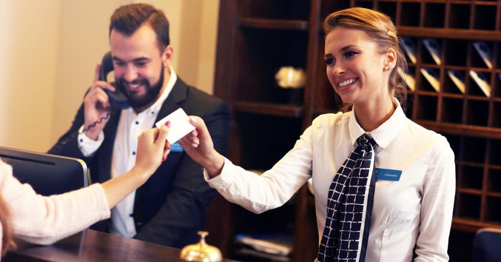 Hotel clerks giving keys to customers who booked their hotels with The Corley Group Travel